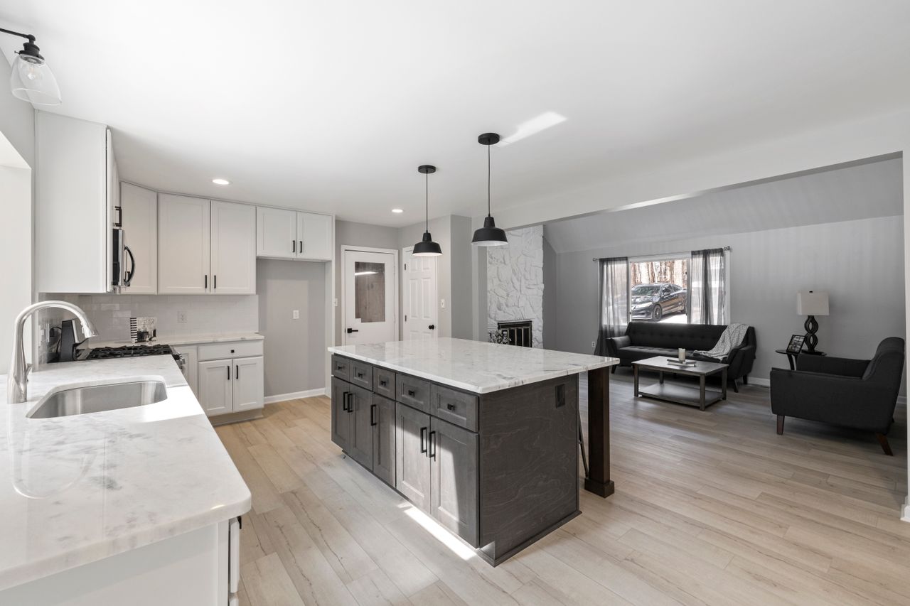 Spacious and stylish open-plan kitchen with marble countertops and modern decor.